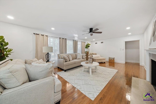 living room with ceiling fan, a high end fireplace, and light hardwood / wood-style flooring