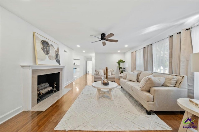 living room featuring ceiling fan, a high end fireplace, and hardwood / wood-style floors