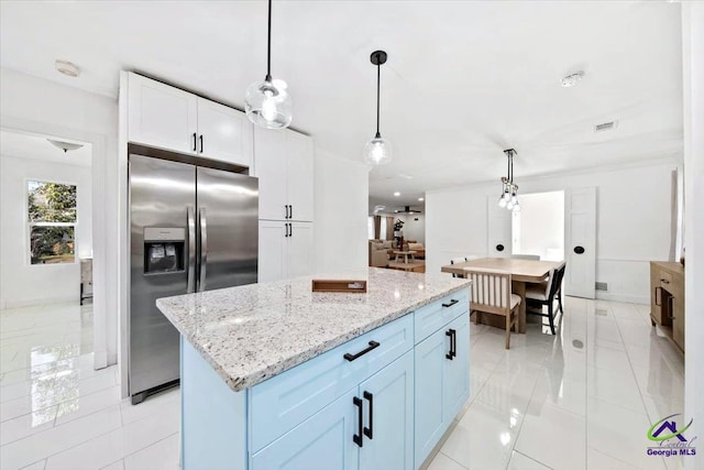 kitchen featuring decorative light fixtures, a center island, stainless steel refrigerator with ice dispenser, white cabinetry, and light tile patterned floors