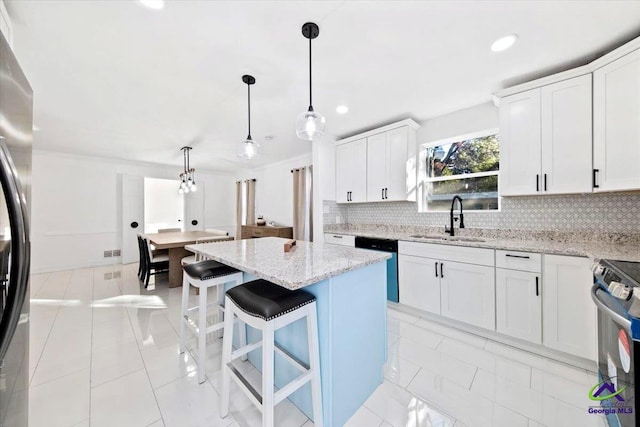 kitchen with pendant lighting, appliances with stainless steel finishes, a center island, white cabinetry, and sink