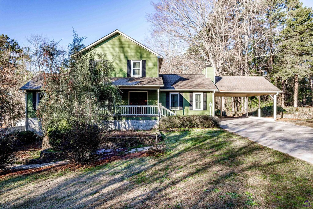 view of front of home featuring a carport, covered porch, and a front lawn