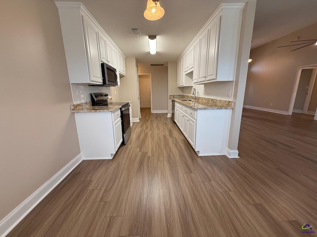 kitchen featuring light stone countertops, white cabinets, appliances with stainless steel finishes, sink, and light wood-type flooring