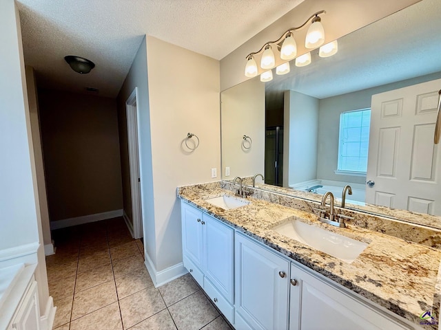 bathroom featuring a textured ceiling, tile patterned floors, a washtub, and vanity