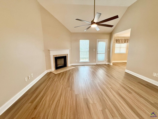 unfurnished living room with vaulted ceiling, ceiling fan, light hardwood / wood-style flooring, and a tiled fireplace