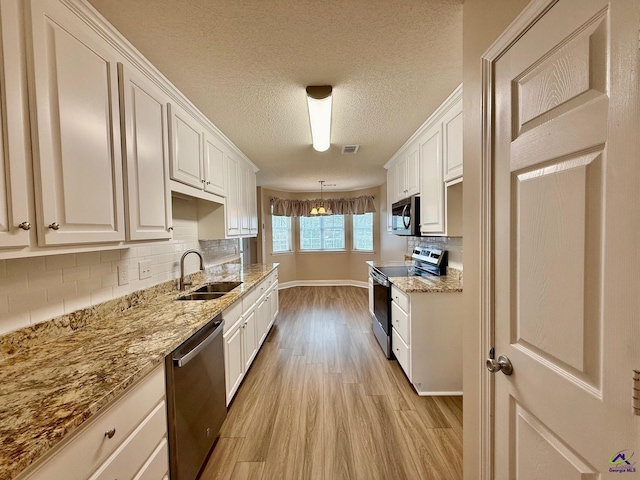 kitchen with appliances with stainless steel finishes, white cabinetry, tasteful backsplash, and sink