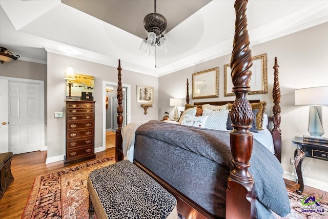 bedroom featuring ceiling fan, crown molding, hardwood / wood-style flooring, and a raised ceiling