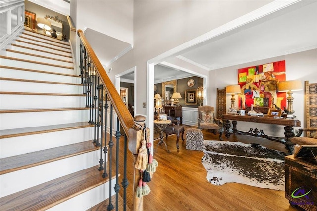 staircase with ornamental molding and hardwood / wood-style flooring