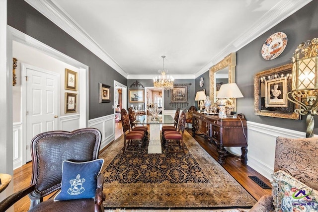 dining space with crown molding, hardwood / wood-style flooring, and a notable chandelier