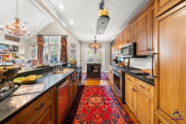 kitchen with an inviting chandelier, appliances with stainless steel finishes, tasteful backsplash, lofted ceiling, and sink