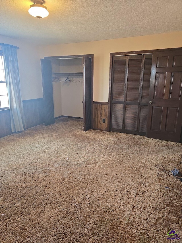 unfurnished bedroom featuring carpet, wood walls, and a textured ceiling