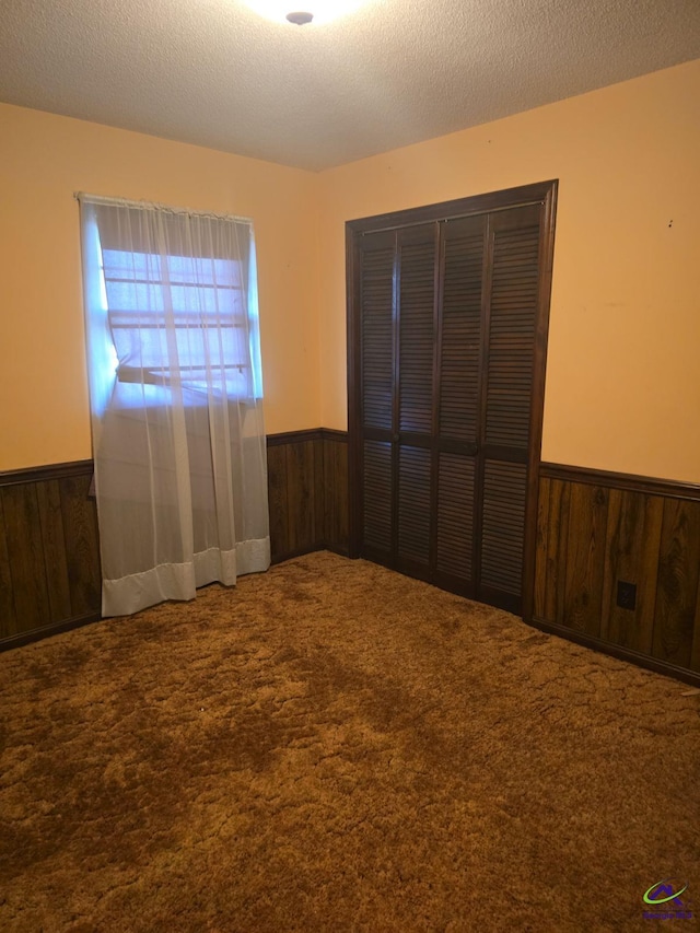 unfurnished bedroom featuring carpet floors, a textured ceiling, and a closet