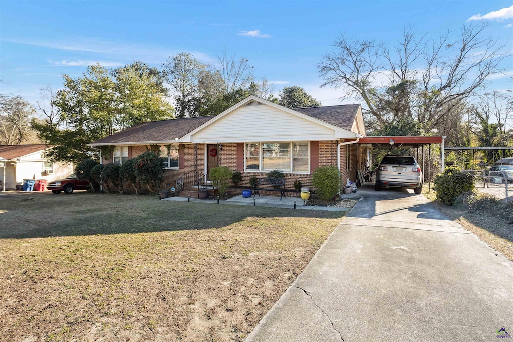 ranch-style home featuring a front lawn and a carport