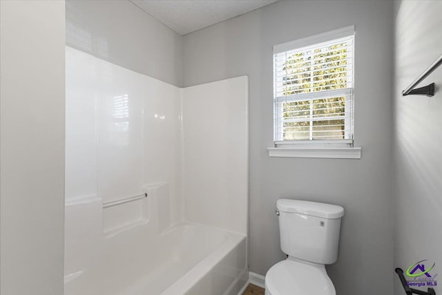 bathroom with a textured ceiling, toilet, and  shower combination