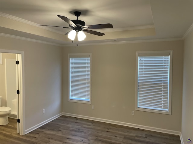 spare room featuring a wealth of natural light, dark wood-type flooring, ornamental molding, a raised ceiling, and ceiling fan