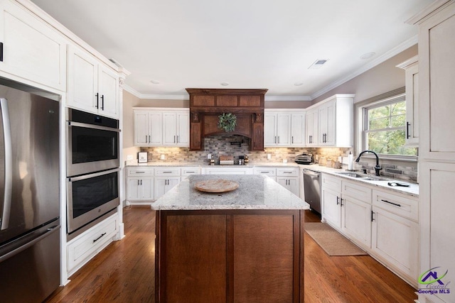 kitchen featuring appliances with stainless steel finishes, a center island, sink, and dark wood-type flooring