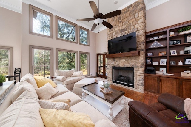 living room featuring a fireplace, hardwood / wood-style flooring, a high ceiling, ceiling fan, and crown molding