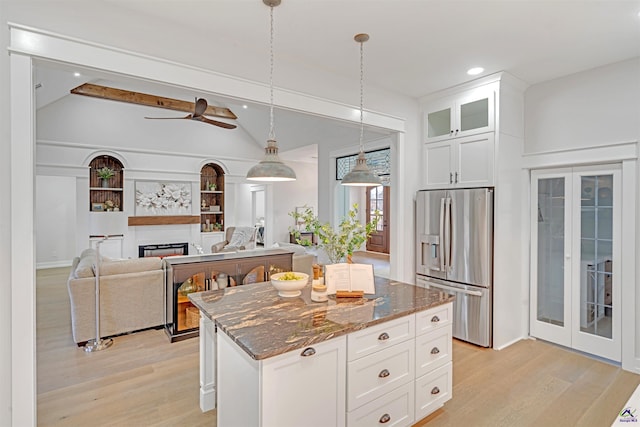 kitchen featuring white cabinets, stainless steel fridge with ice dispenser, dark stone countertops, and a kitchen island