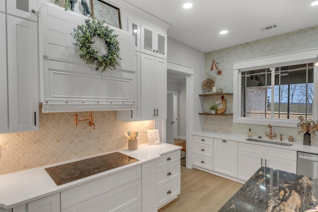 kitchen with black electric stovetop, backsplash, white cabinets, and sink