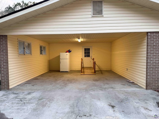 garage with a carport and white fridge