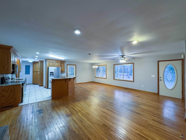 kitchen with range with electric stovetop, light hardwood / wood-style floors, stainless steel refrigerator with ice dispenser, a kitchen island, and sink