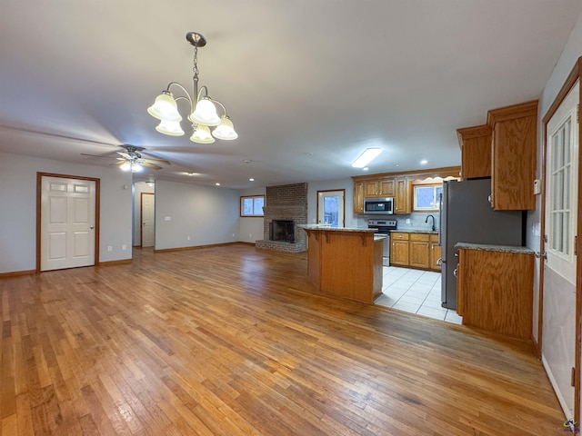 kitchen featuring a breakfast bar area, appliances with stainless steel finishes, hanging light fixtures, ceiling fan with notable chandelier, and sink