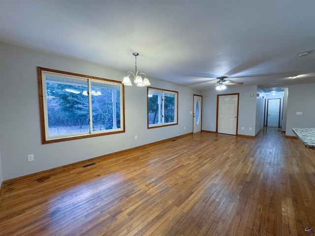 unfurnished living room with ceiling fan with notable chandelier and hardwood / wood-style floors