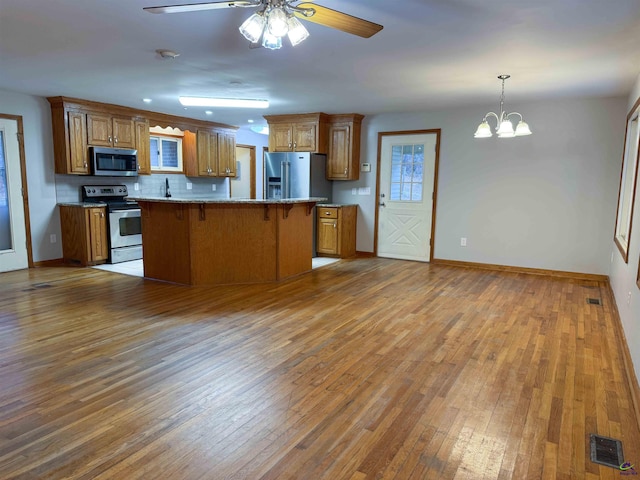 kitchen featuring appliances with stainless steel finishes, decorative backsplash, a kitchen bar, and hardwood / wood-style flooring