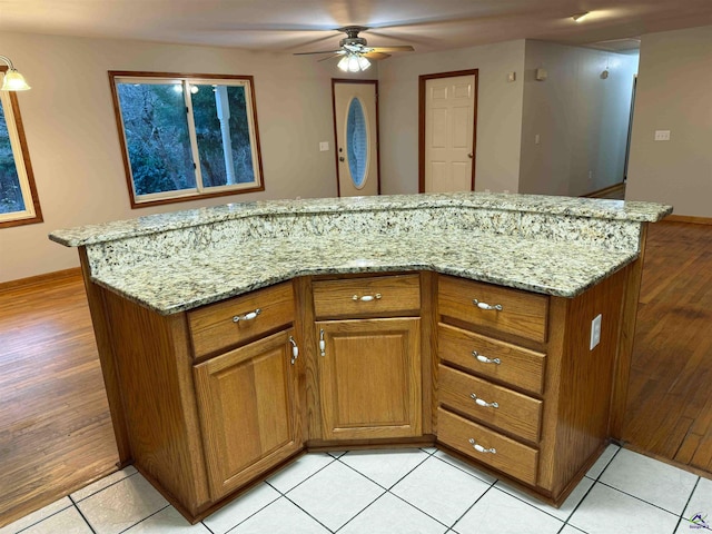 kitchen with ceiling fan, light stone counters, and light tile patterned floors