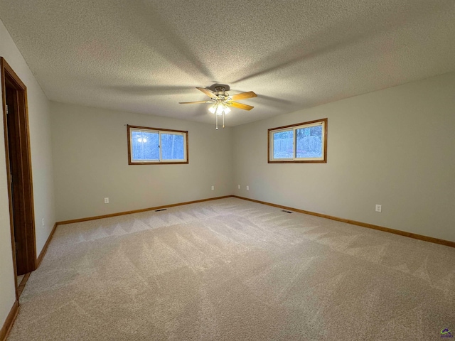 unfurnished room featuring a textured ceiling, ceiling fan, a wealth of natural light, and light colored carpet