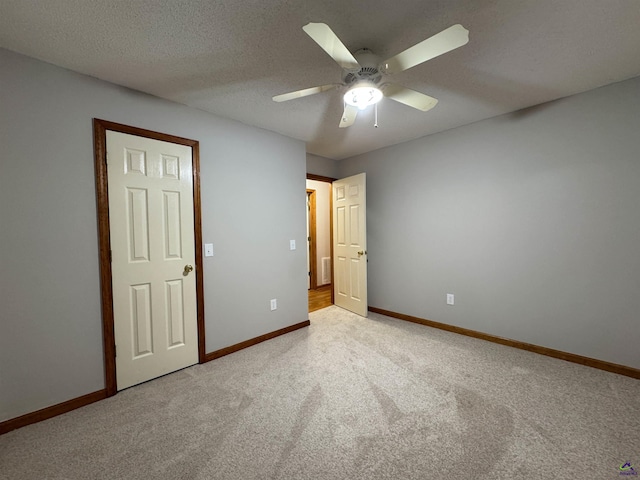 unfurnished bedroom with ceiling fan, light colored carpet, and a textured ceiling