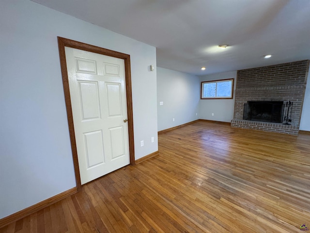 unfurnished living room featuring a brick fireplace and wood-type flooring