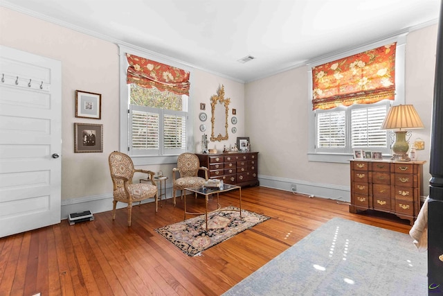 living area with crown molding and hardwood / wood-style flooring