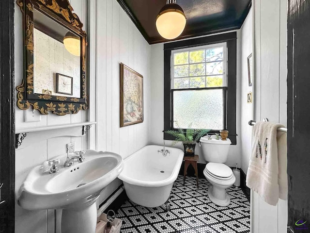 bathroom featuring a tub to relax in, sink, tile patterned floors, and toilet