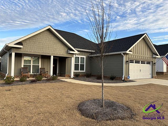 view of front of property featuring a garage, a front yard, and a porch