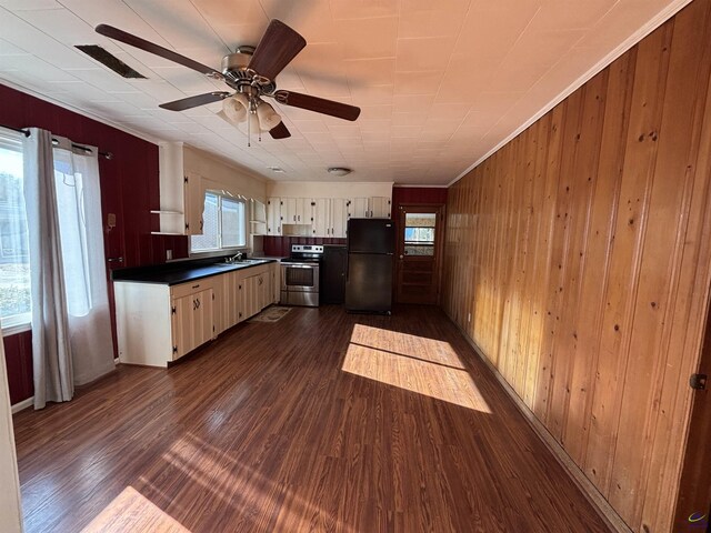 570 Perry Hwy, Hawkinsville, GA 31036 - kitchen featuring ceiling fan, dark hardwood / wood-style floors, black fridge, wooden walls, and stainless steel range with electric cooktop