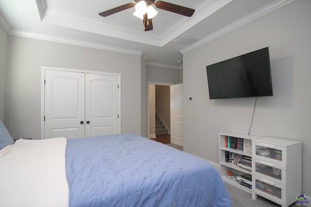 bedroom with ceiling fan, a closet, crown molding, and a raised ceiling