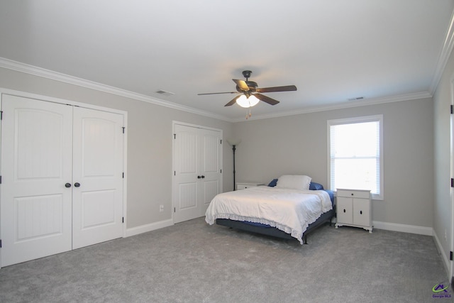 carpeted bedroom with ceiling fan, crown molding, and multiple closets