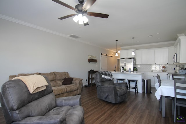 living room featuring ceiling fan, ornamental molding, a barn door, and dark hardwood / wood-style floors