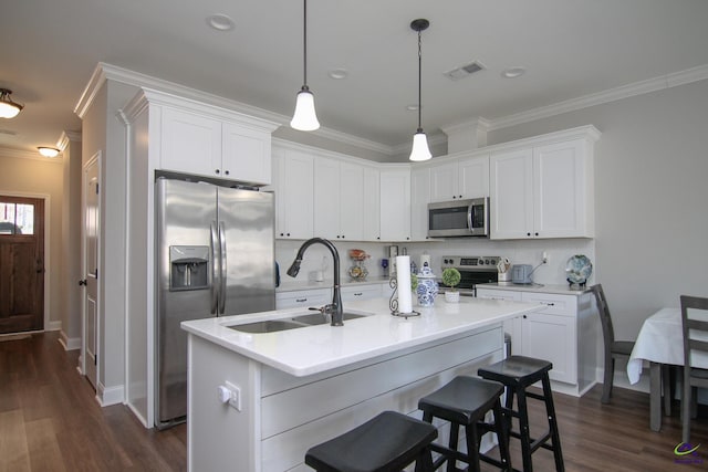 kitchen featuring white cabinets, stainless steel appliances, tasteful backsplash, sink, and a center island with sink