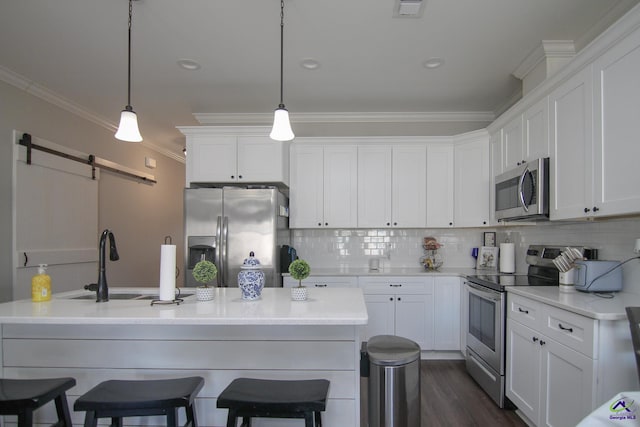 kitchen with white cabinetry, a barn door, stainless steel appliances, backsplash, and hanging light fixtures