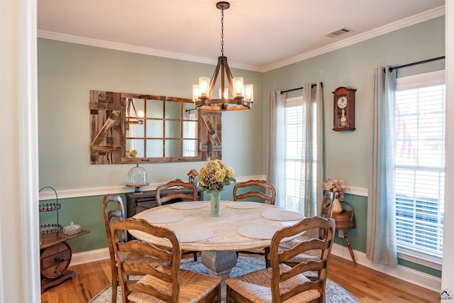 dining room with ornamental molding, light hardwood / wood-style floors, and a notable chandelier