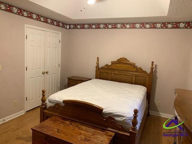 bedroom with a closet, a textured ceiling, and hardwood / wood-style floors