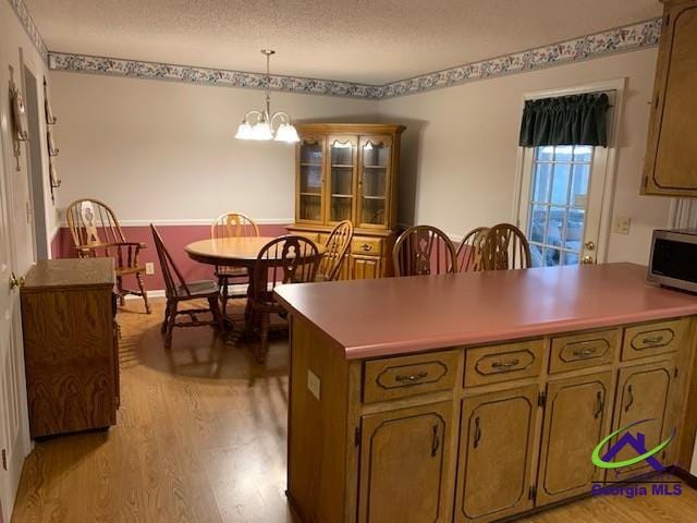 kitchen featuring light hardwood / wood-style flooring, a notable chandelier, a textured ceiling, and pendant lighting