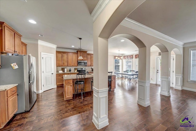 kitchen with decorative light fixtures, a kitchen island, a kitchen breakfast bar, stainless steel appliances, and light stone counters