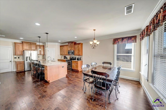 dining room with a notable chandelier, sink, ornamental molding, and dark hardwood / wood-style floors