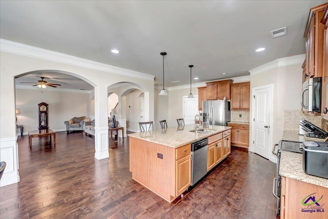 kitchen with stainless steel appliances, sink, backsplash, hanging light fixtures, and a kitchen island with sink