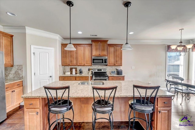 kitchen featuring appliances with stainless steel finishes, sink, pendant lighting, and a center island with sink