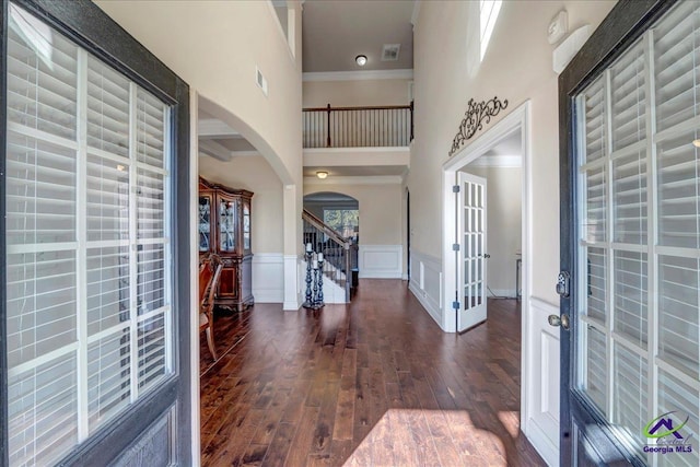 entryway featuring dark hardwood / wood-style floors, a towering ceiling, and ornamental molding