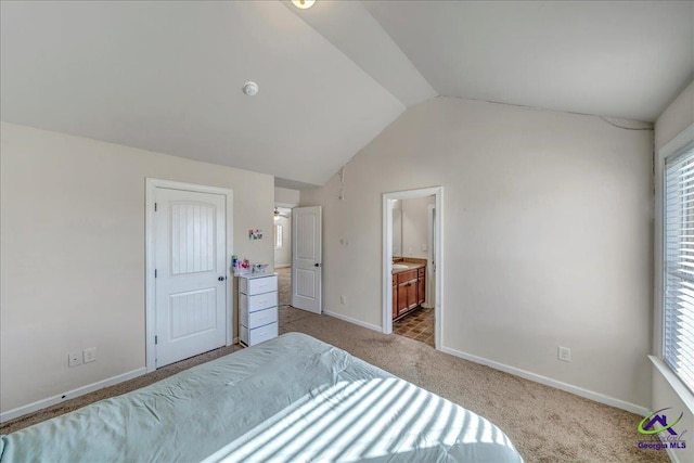 bedroom featuring vaulted ceiling, ensuite bathroom, and light carpet