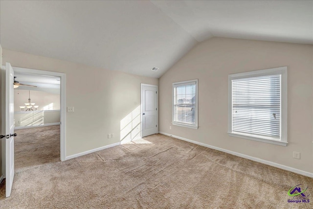 unfurnished bedroom featuring light carpet, a chandelier, and lofted ceiling